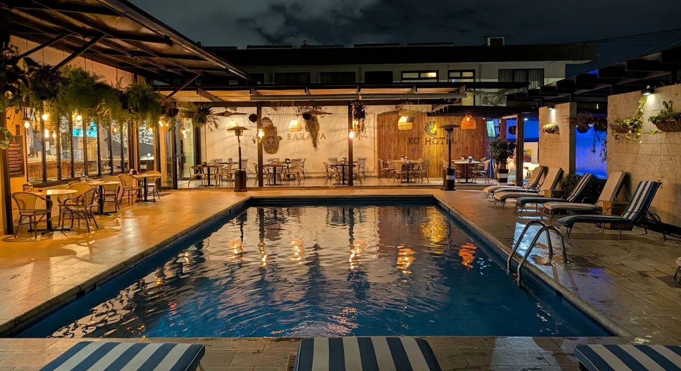 Piscina de KC Hotel iluminada de noche, con tumbonas a rayas