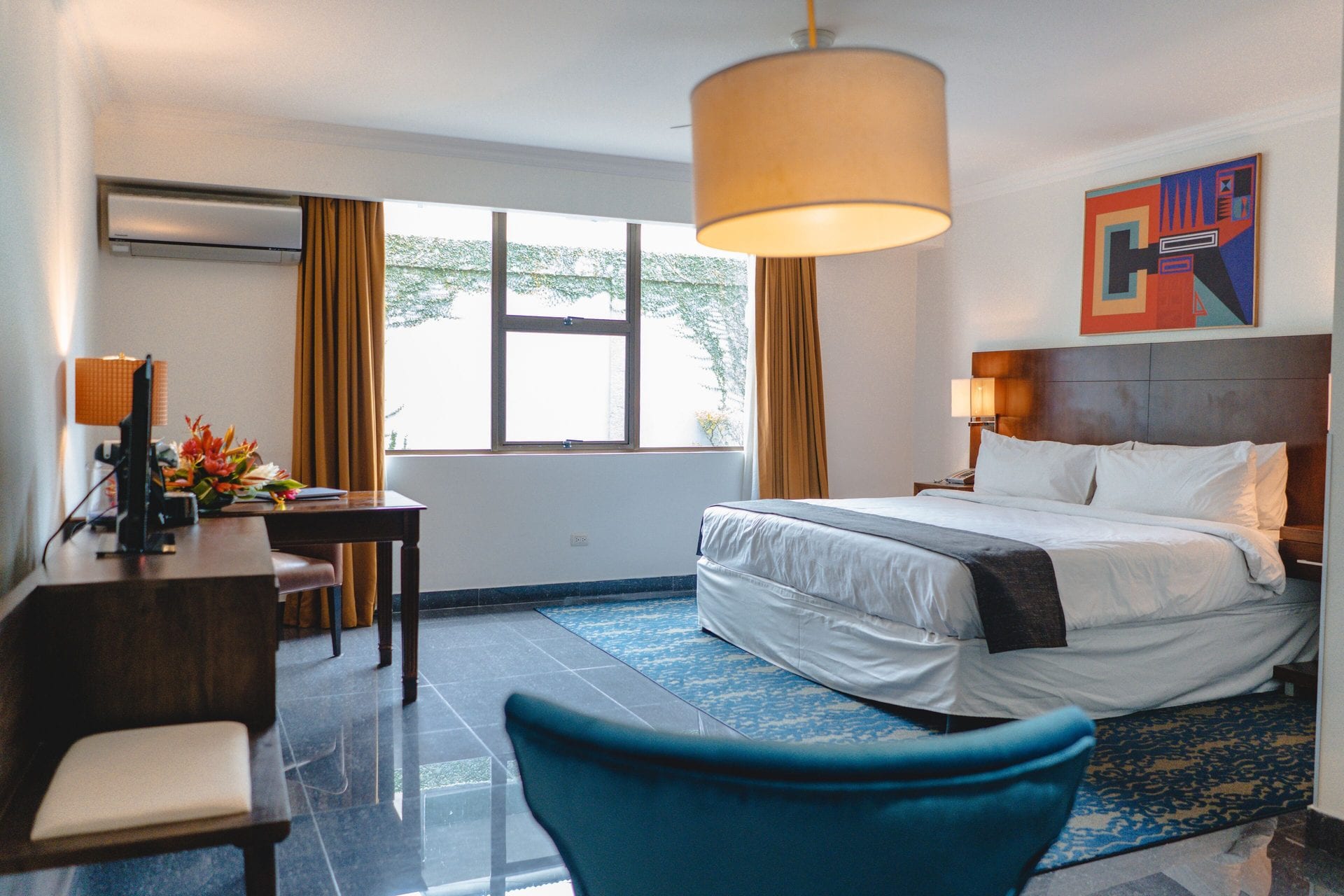 Cama king y escritorio de madera de la Superior King, con sillón azul y ventana al jardín