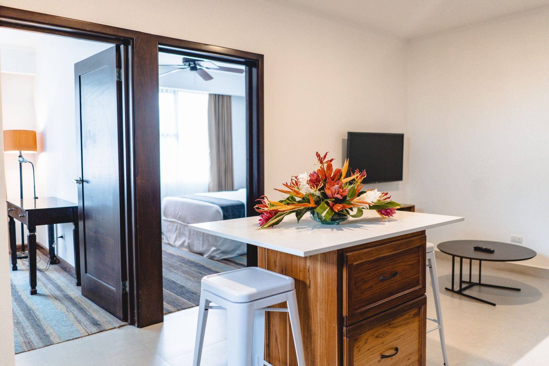 Barra con dos bancos y escritorio en la sala del Apartamento Familiar, con el dormitorio abierto al fondo