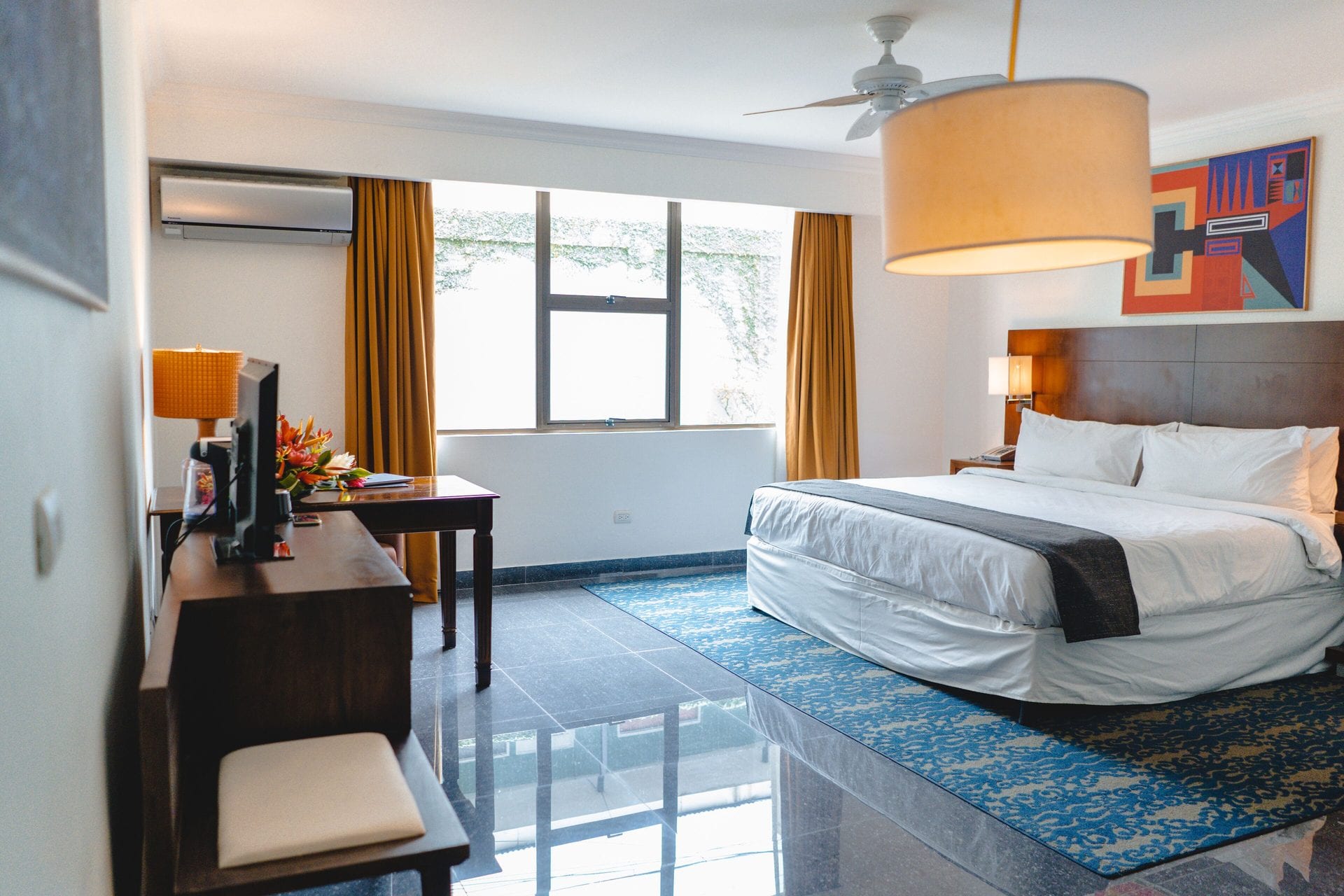 Vista amplia de la Superior King: cama king, zona de escritorio y piso de granito