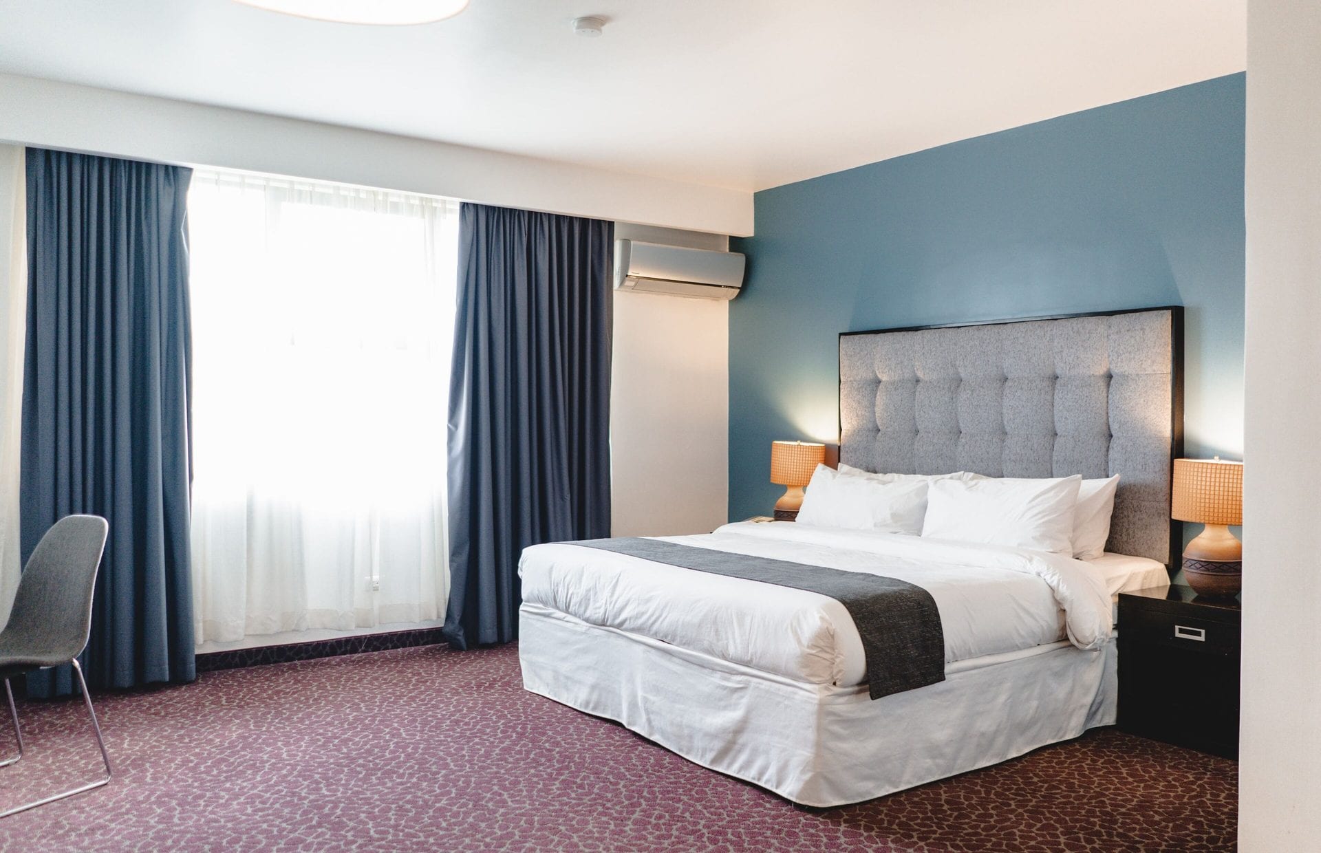 Junior Suite King con cama king, ventanal de piso a techo y silla junto a la ventana
